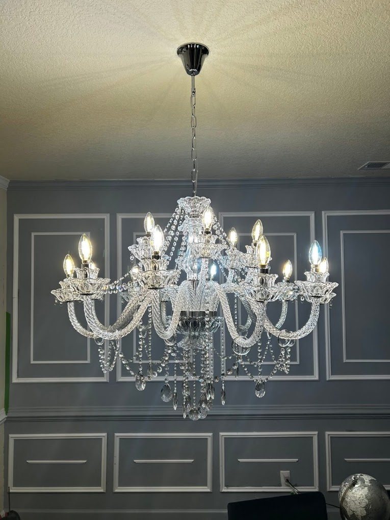 A crystal chandelier hung in a room with white wall molding.