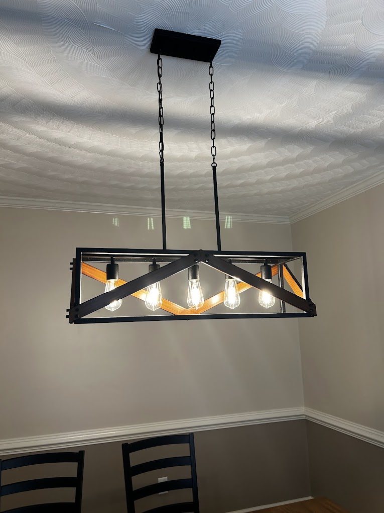 A black and wood linear light fixture hung over a dining table.