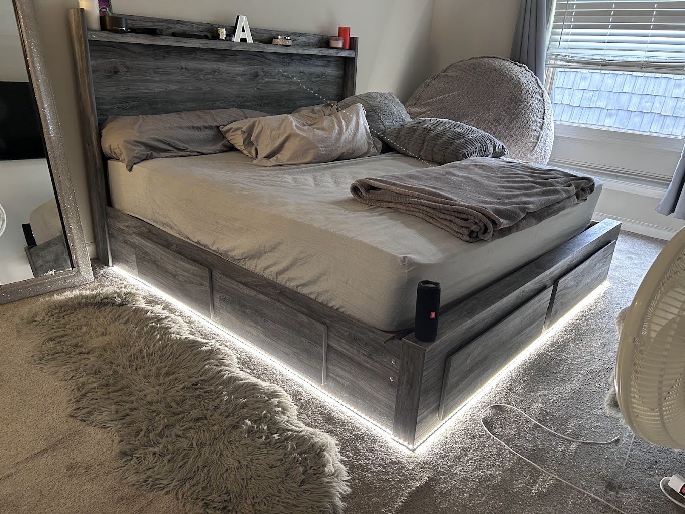 White LED strip lighting glowing along the base of a bed frame.