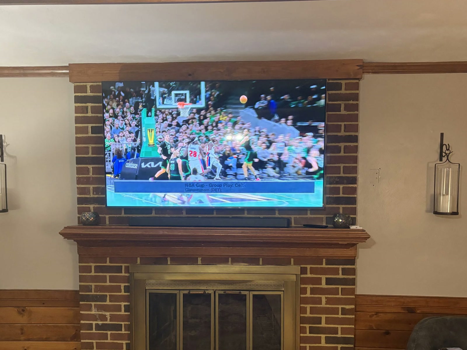 A 65 inch TV mounted over a brick fireplace with the wires fully hidden.